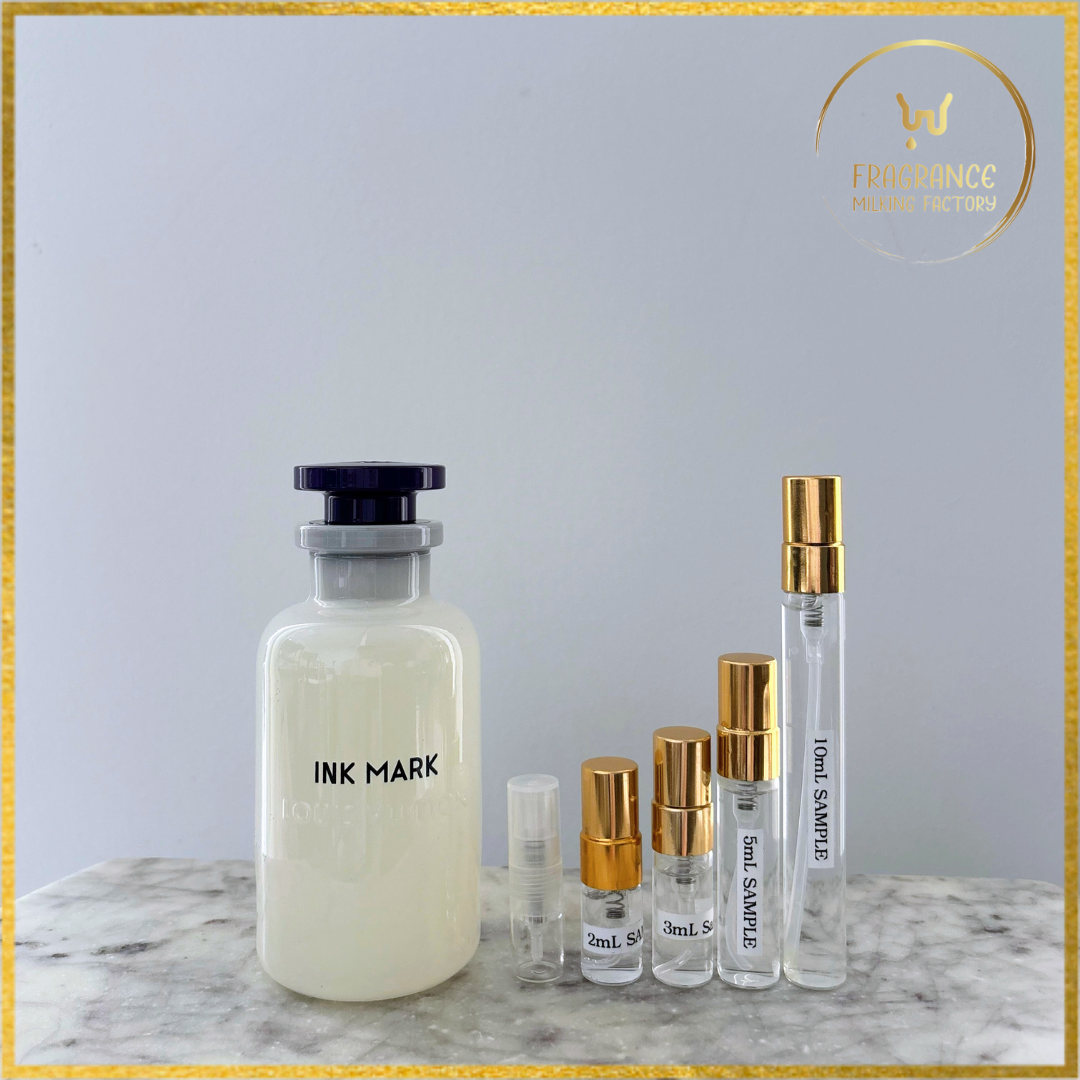 Collection of perfume bottles including a large 'INK MARK' bottle and smaller sample bottles on a marble surface.