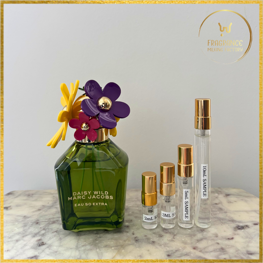 Green perfume bottle with floral design and smaller sample bottles on a marble surface.